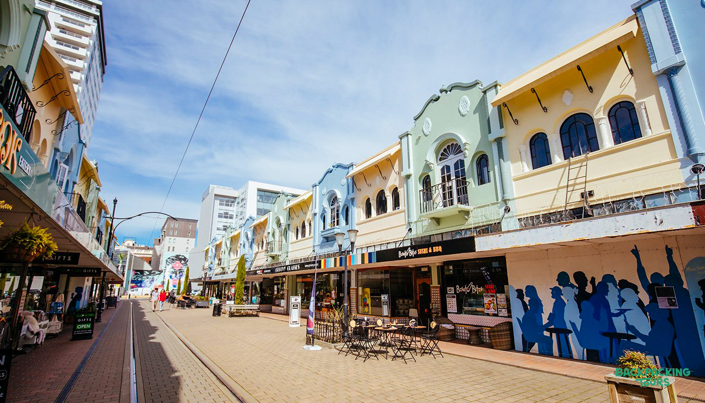 A charming street lined with colorful pastel buildings housing shops and cafes on a sunny day.