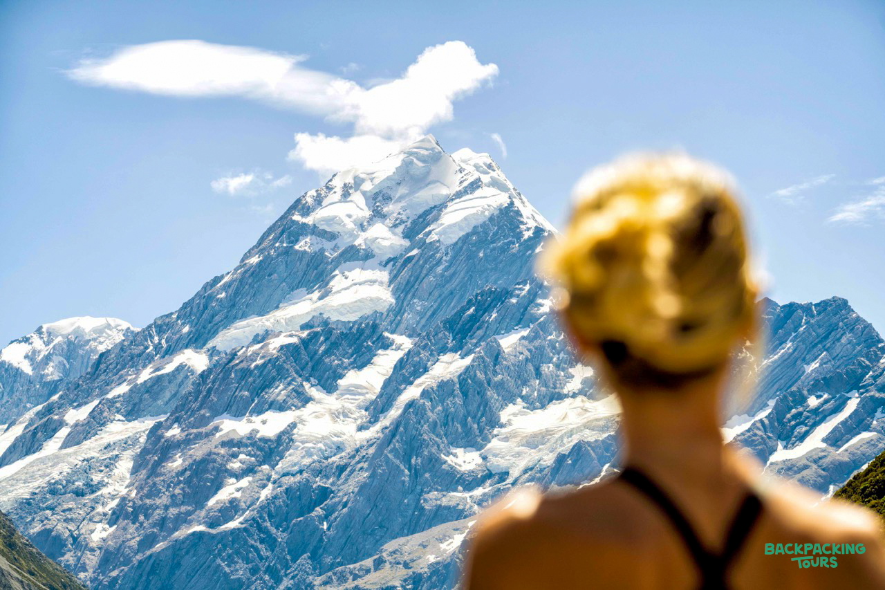 A hiker admires the majestic, snow-capped Aoraki Mount Cook from the Hooker Valley Track.
