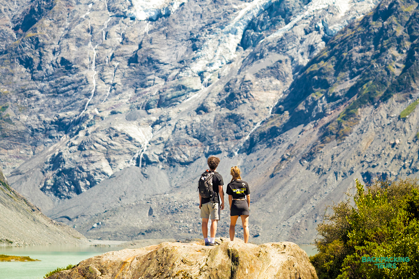 Two hikers admire the stunning glacial landscape of Hooker Valley in Mount Cook National Park.