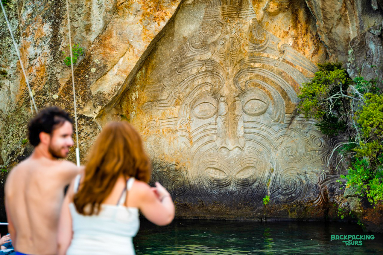 Visitors on a boat admiring the impressive Māori rock carvings on Lake Taupo.