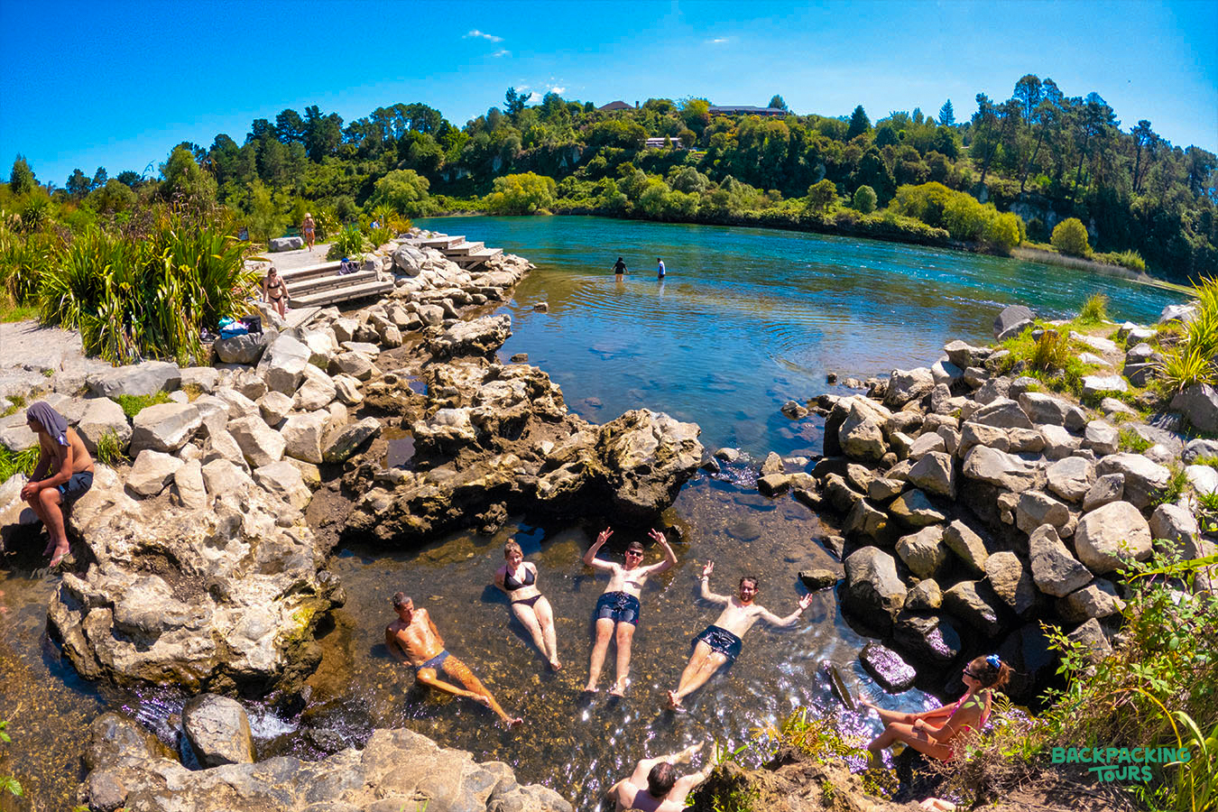 Travelers relax in the warm geothermal waters of a natural hot spring in Taupo, New Zealand.