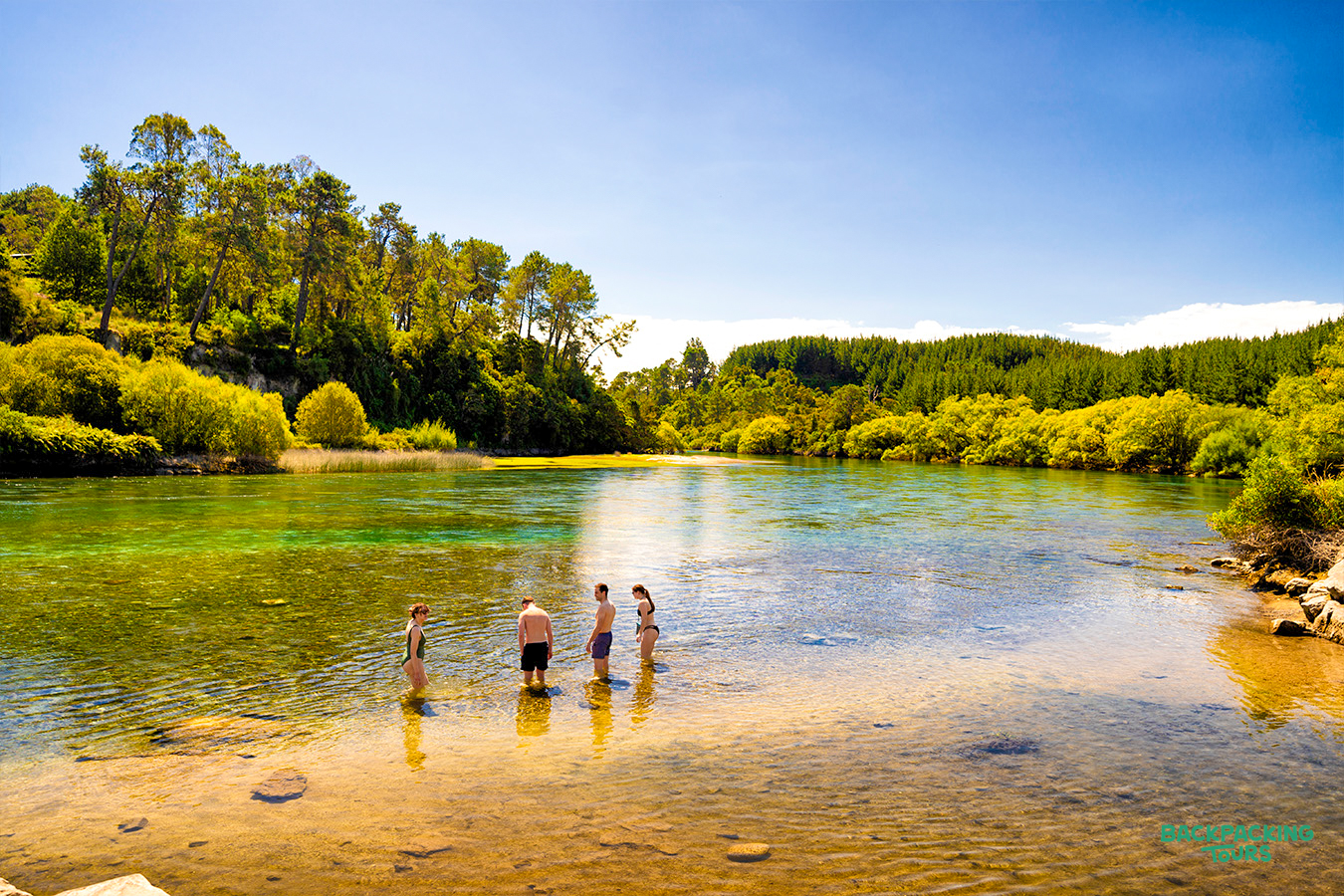 Friends cool off in the clear, green waters of a beautiful river near Taupo, New Zealand.