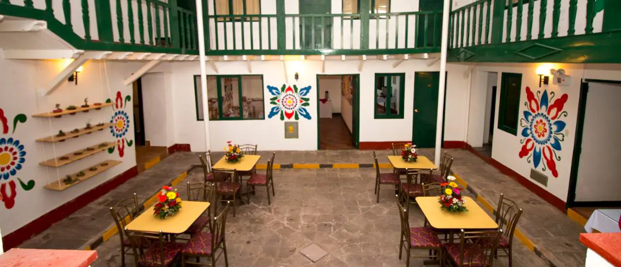 A vibrant hotel courtyard in Cusco featuring colorful murals and tables set for dining.