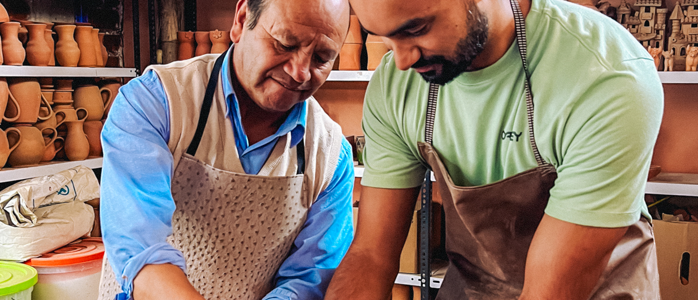 Two men in aprons focused on creating pottery during a traditional workshop in Cusco.