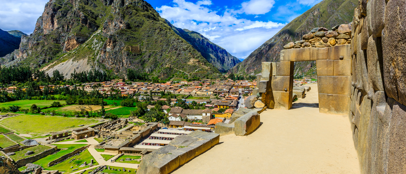 Historic stone ruins frame a panoramic view of Ollantaytambo town and mountains in the Sacred Valley.