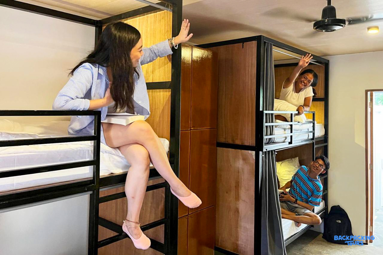Travelers relax and wave to each other in a modern capsule-style hostel dorm room in Bohol.