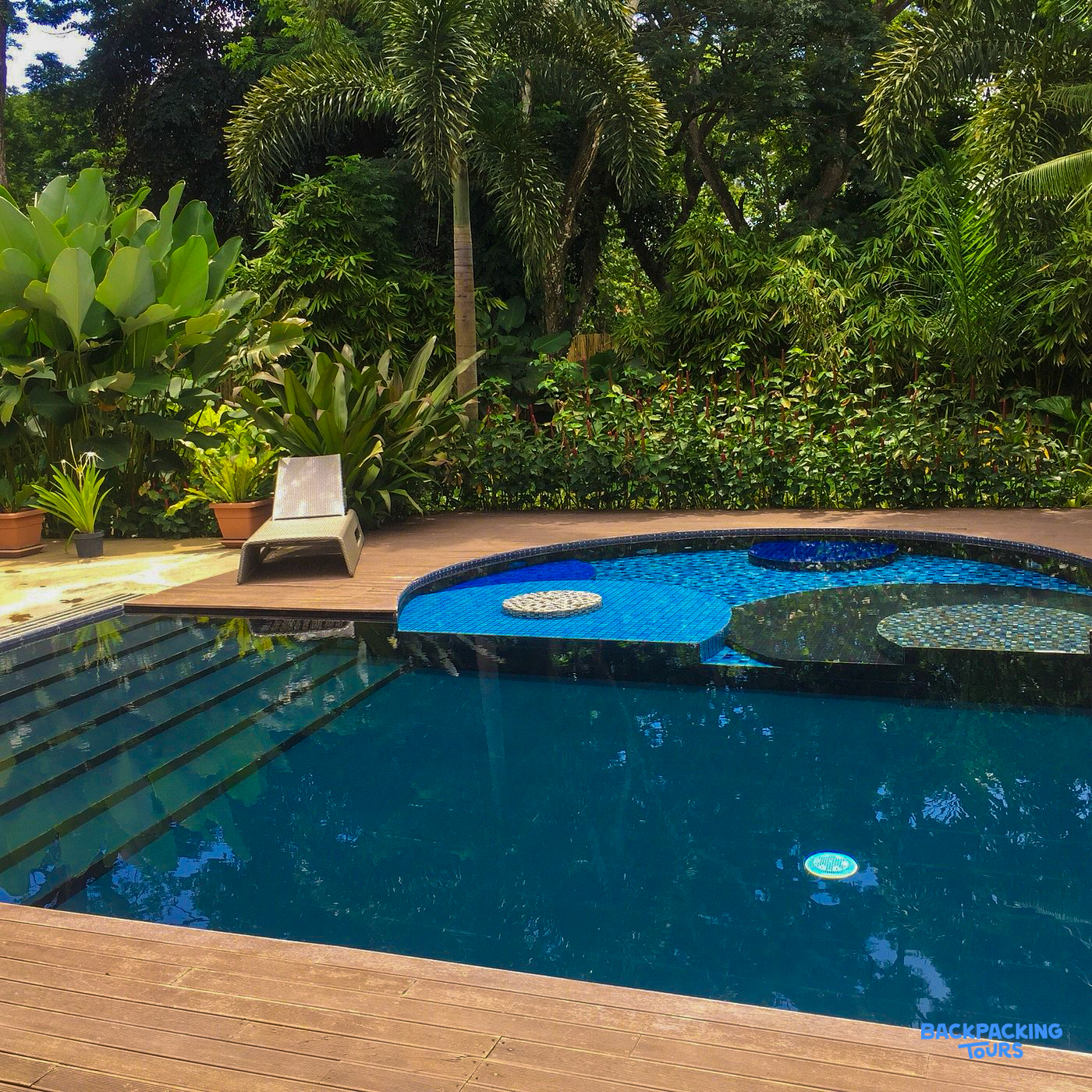 A refreshing swimming pool with a wooden deck and lush tropical plants in Puerto Princesa.