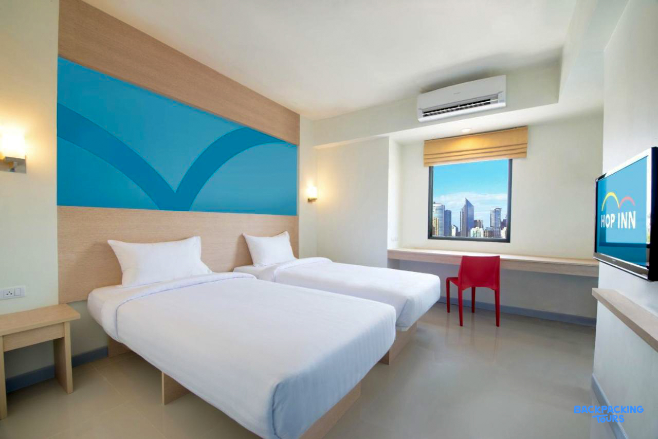 A clean and modern twin room in Cebu City, featuring a desk and city skyline view.