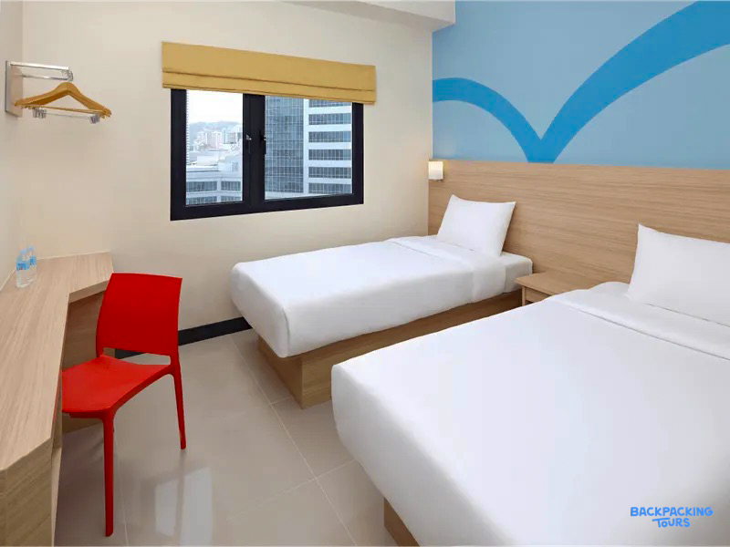 Modern twin hotel room in Cebu City with two single beds, a desk, and city views.