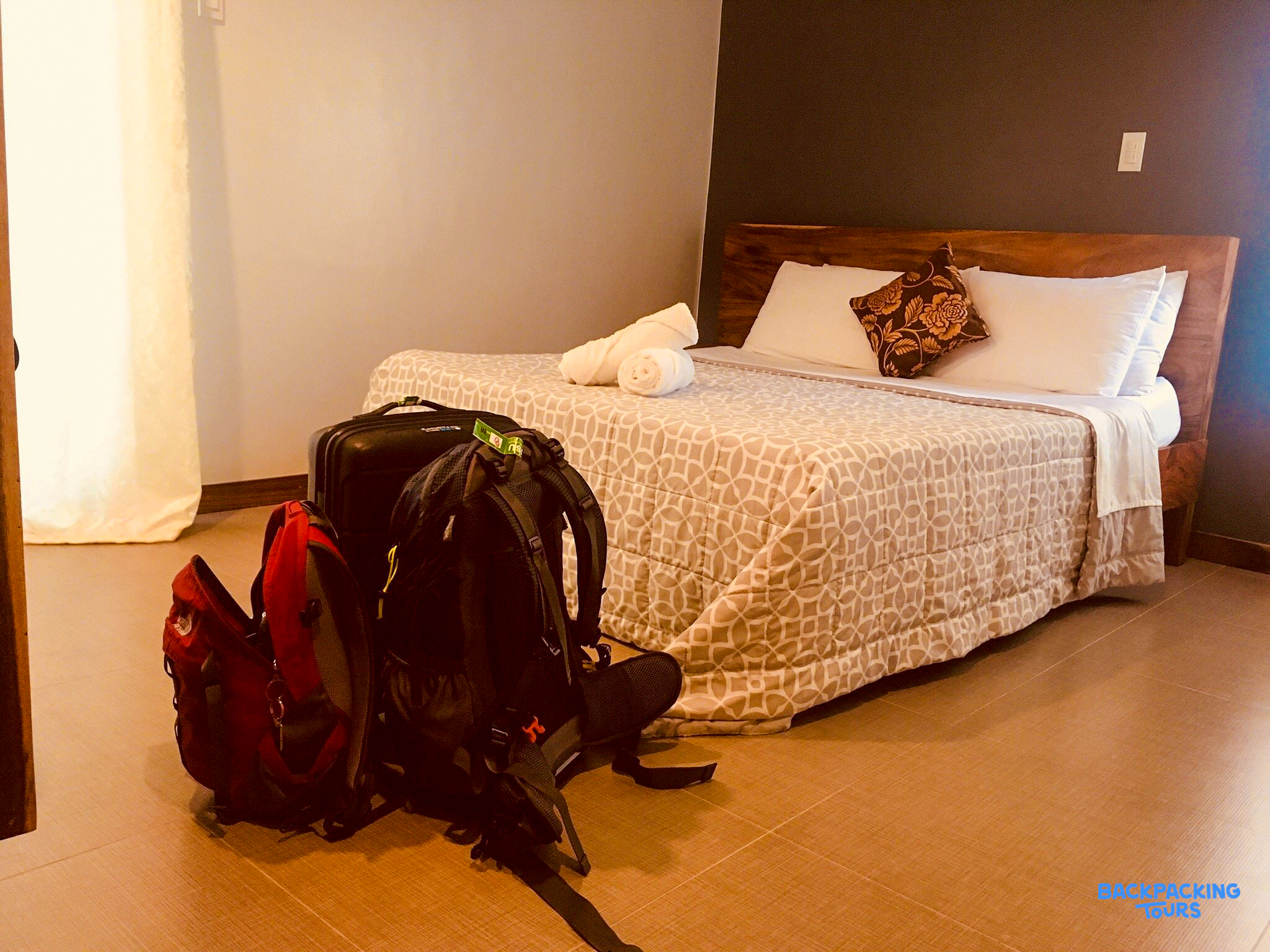 A comfortable hotel room with a bed and travel bags, ready for the next adventure.