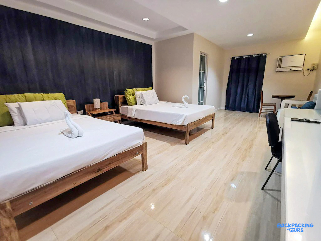 A bright and inviting twin room in Moalboal, featuring modern wooden beds and a dark accent wall.