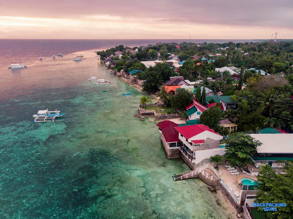 Stunning aerial view of the Moalboal coastline with clear water, boats, and beachfront accommodations.