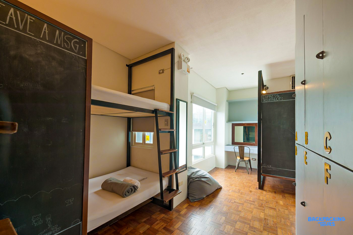 A bright and clean hostel dorm room in Manila with bunk beds, a desk, and personal lockers.