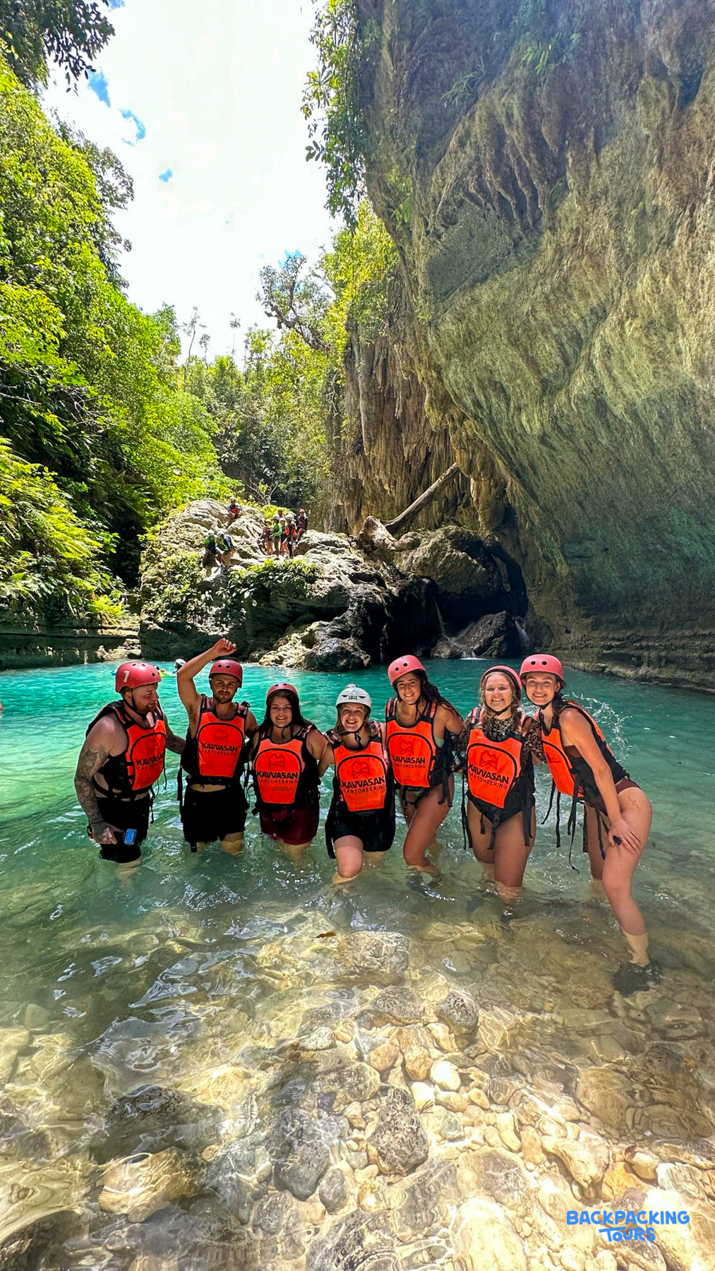 A group of happy friends in life vests enjoying the clear turquoise waters of Cambais Falls, Cebu.