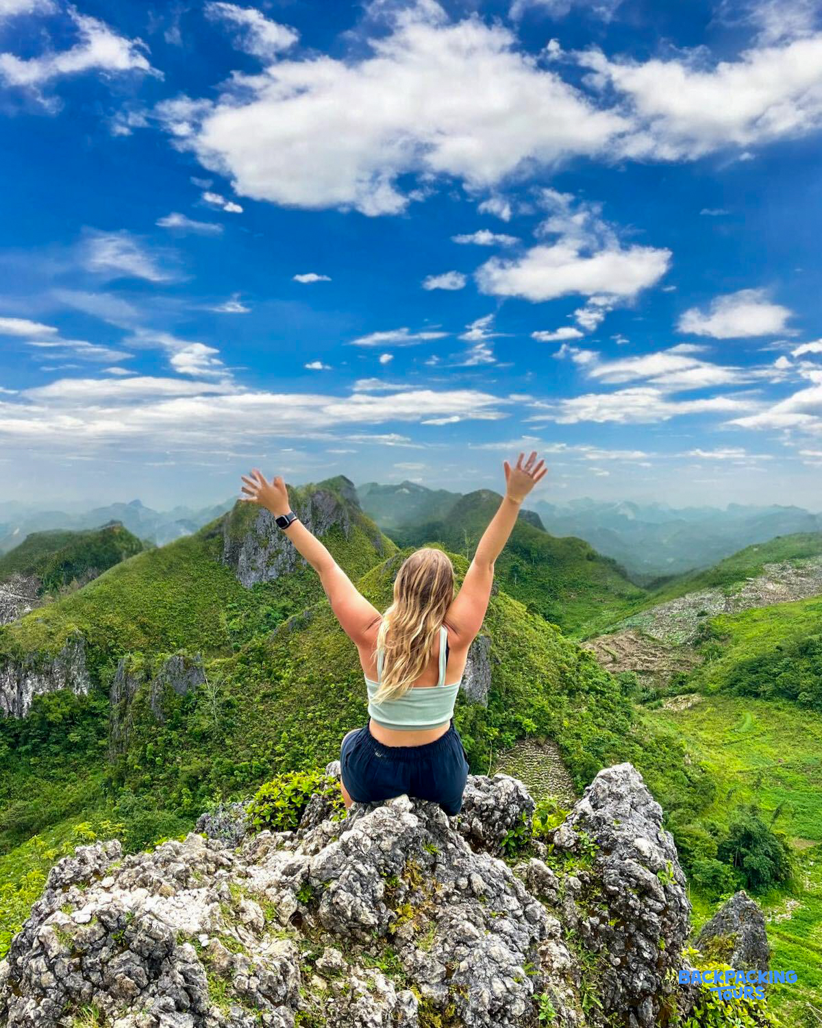 A happy traveler with arms outstretched enjoys panoramic views of Bohol's green Chocolate Hills.
