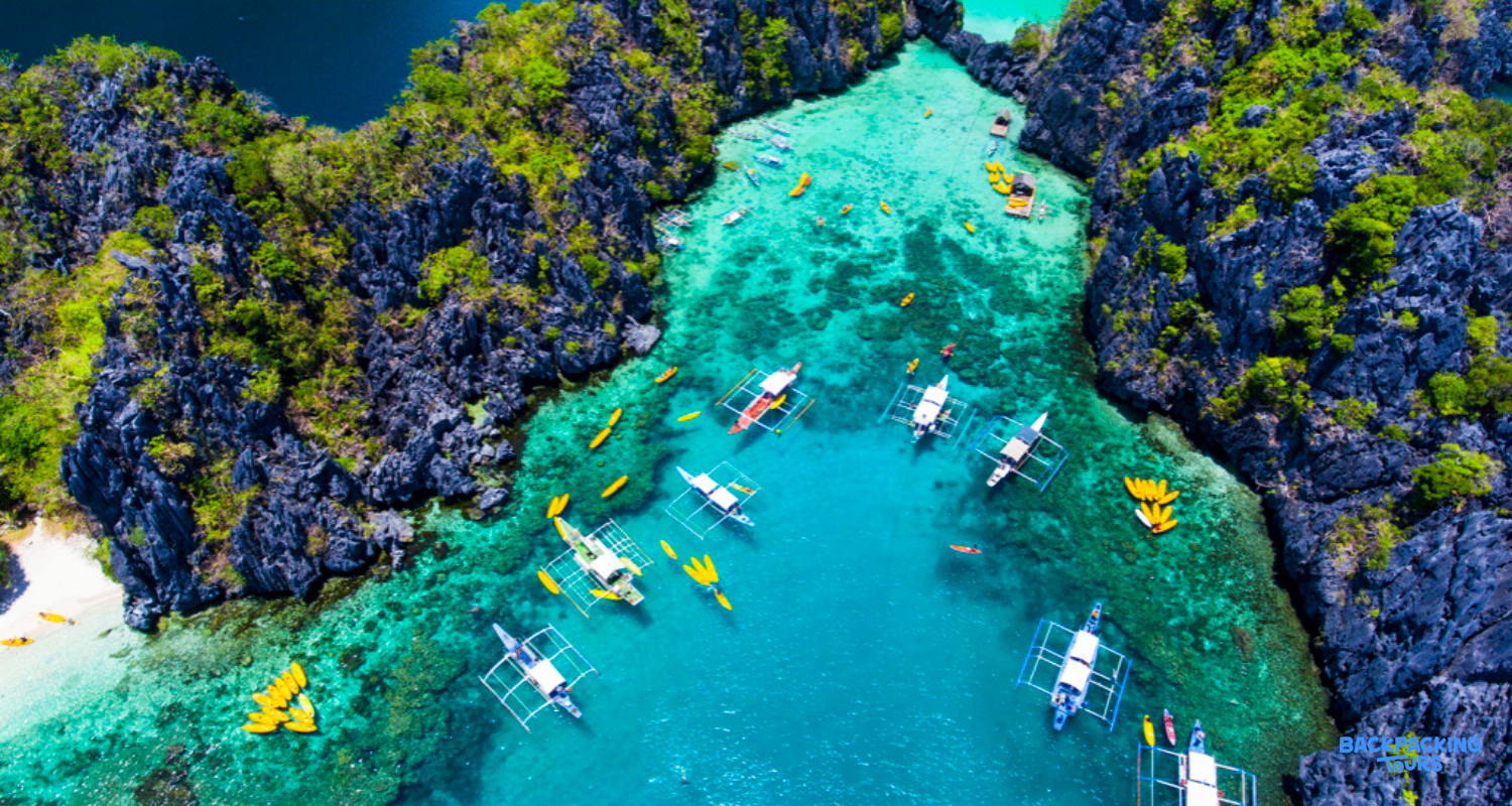Traditional boats and kayaks navigate the stunning turquoise lagoons and rocky islands of Coron, Philippines.