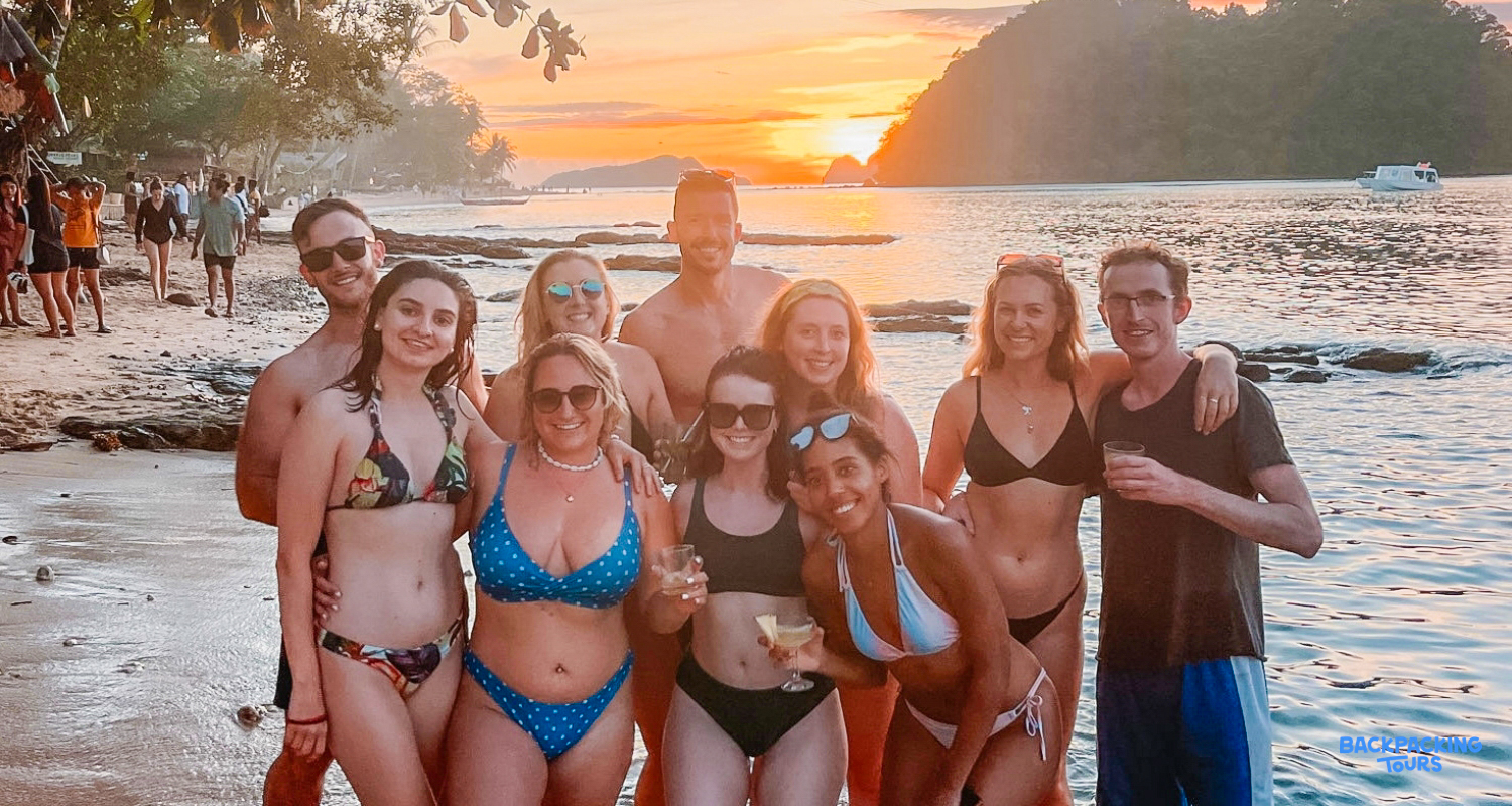 A happy group of friends pose on a beautiful beach at sunset in Coron, Philippines.
