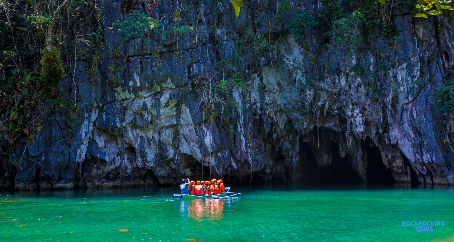 Adventurers in a small boat approaching the majestic entrance of the Puerto Princesa Underground River.