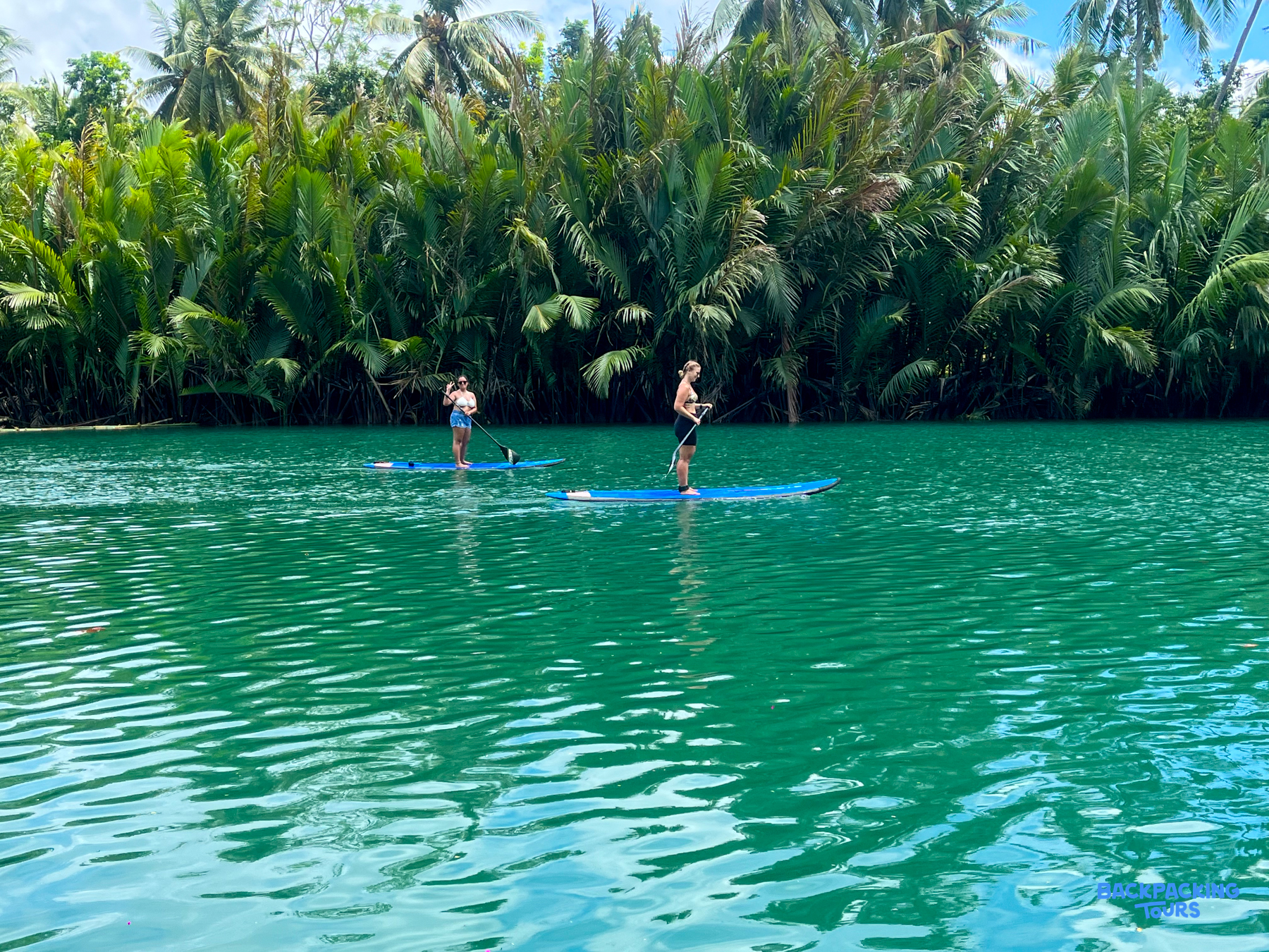 Enjoying a peaceful paddleboarding adventure on the stunning green Loboc River, surrounded by tropical trees in Bohol.
