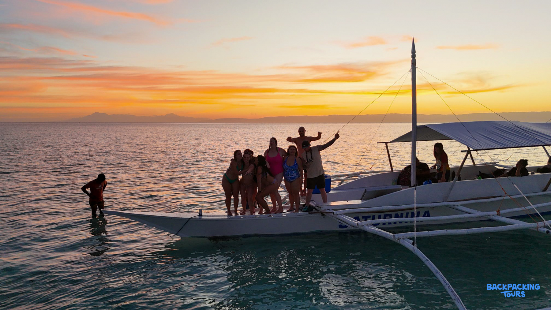 Happy friends on a traditional outrigger boat enjoying a stunning sunset in Boracay.