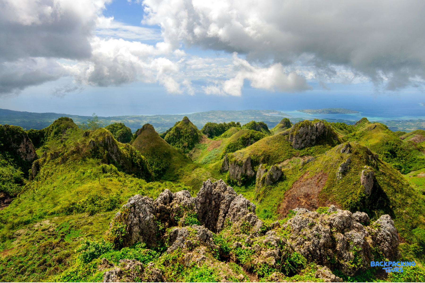 Sweeping view of the unique rugged green hills of Osmena Peak in Cebu, with the ocean in the distance.