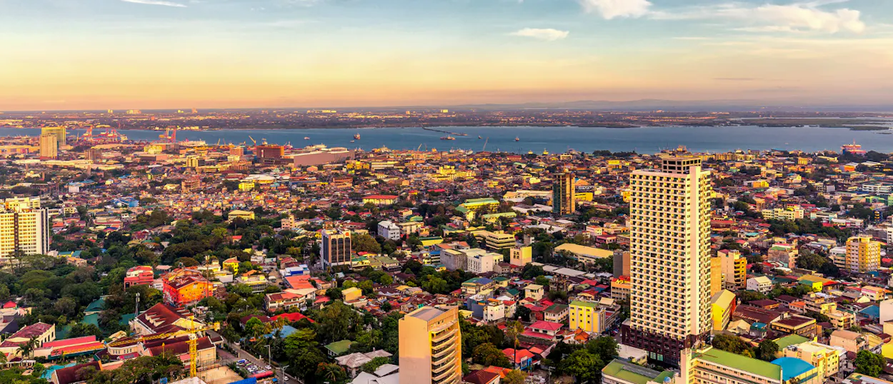 Cebu City skyline at golden hour, with numerous buildings stretching to the distant bay.