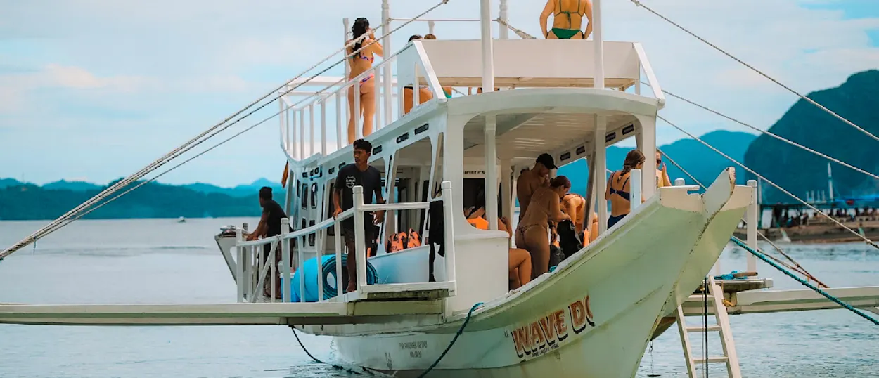 Tourists relaxing on a traditional bangka boat, cruising the clear waters near El Nido, Philippines.