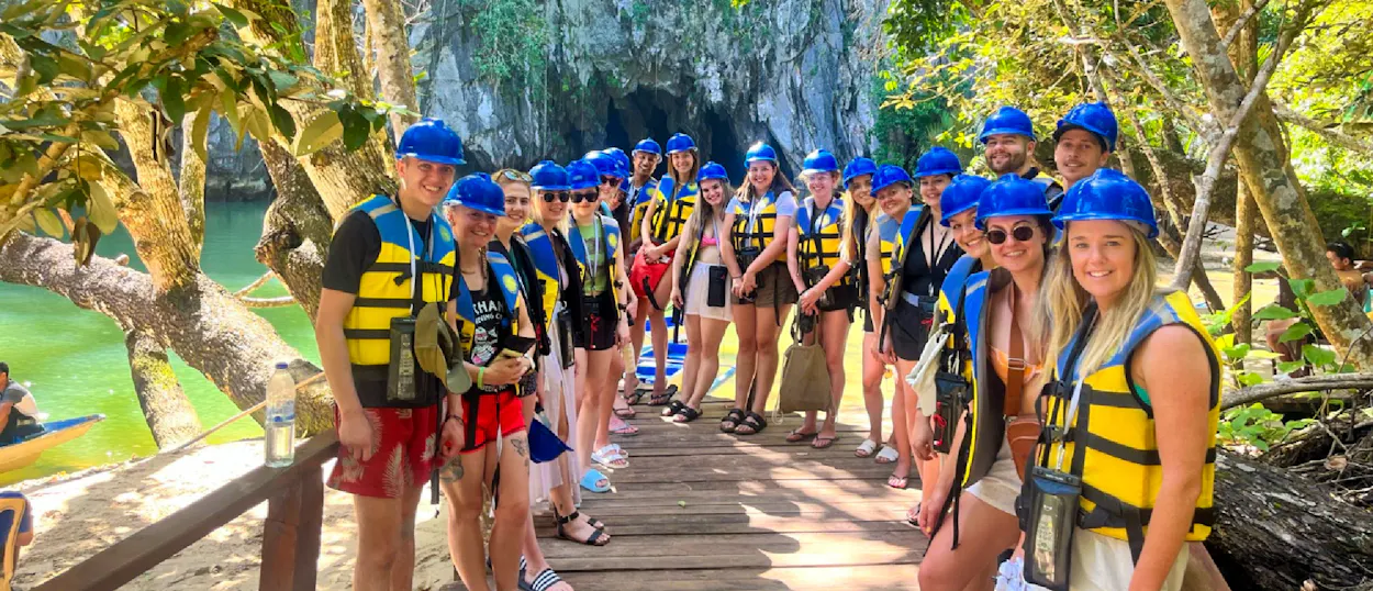 A group of excited backpackers in helmets and life vests ready to explore the Underground River.