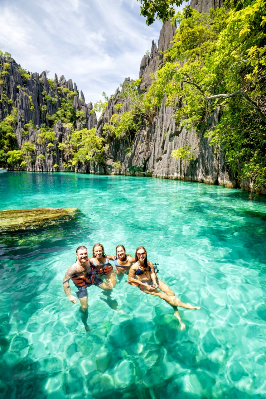 A group of backpackers swimming together in a hidden lagoon in the Philippines.