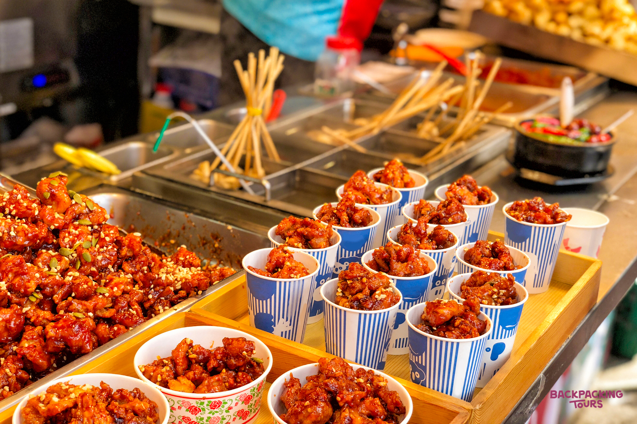 Sweet and spicy Korean fried chicken served in cups at a lively street food stall in Seoul.