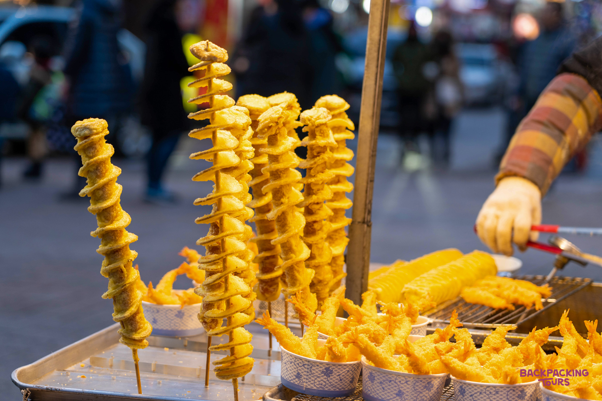 Delicious spiral-cut potatoes and fried shrimp at a bustling street food stall in Seoul.