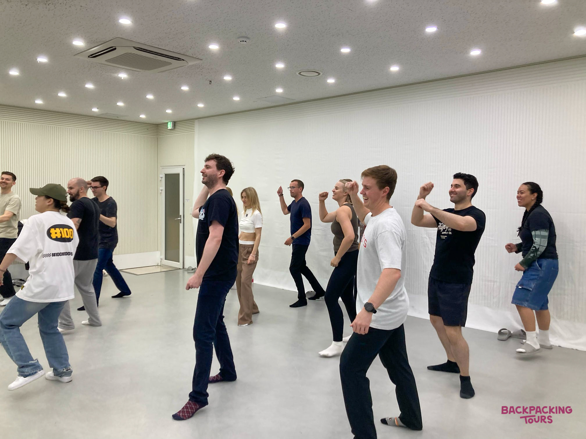 Travelers learn K-pop dance moves with an instructor in a modern, brightly lit studio in Seoul.