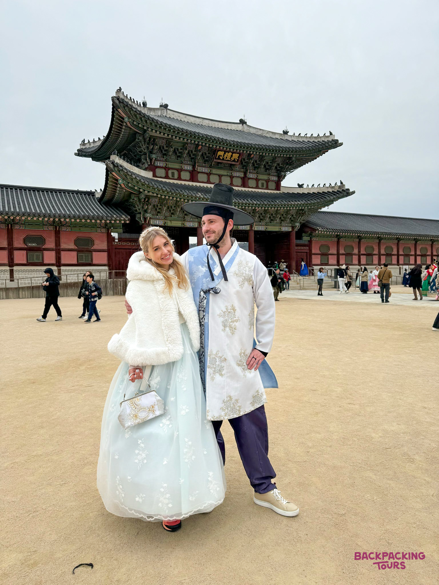 Smiling couple in traditional hanbok enjoying the historic Gyeongbokgung Palace in Seoul.