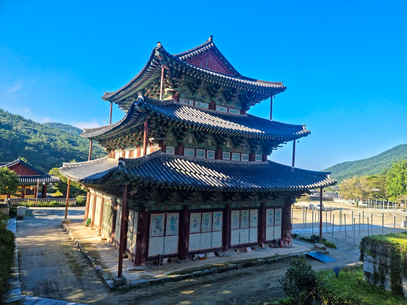 A beautiful multi-tiered temple at Geumsunsa stands peacefully amidst green mountains under a clear blue sky.