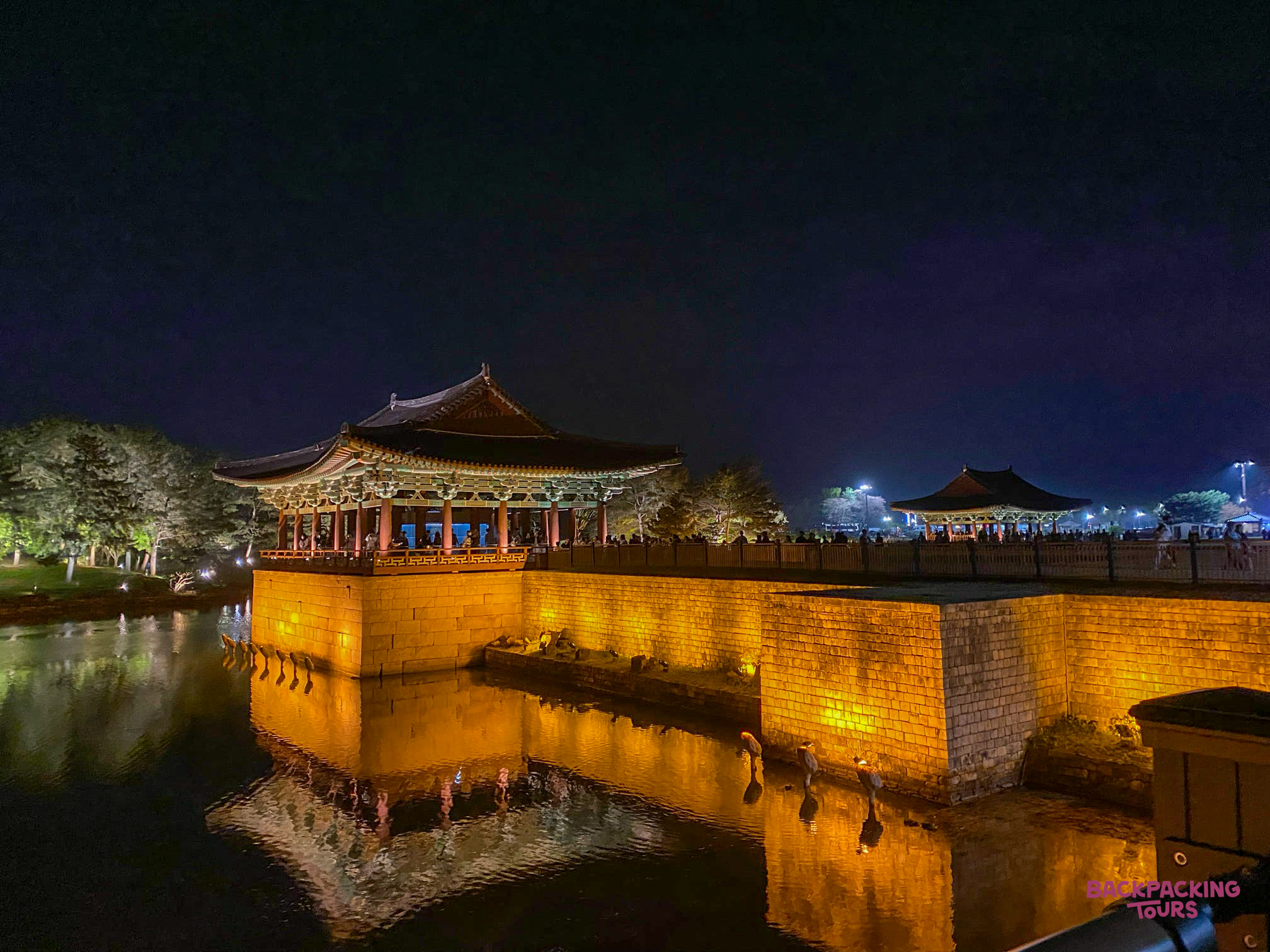 Traditional Korean pavilions beautifully illuminated at night, reflected in the still waters of Anapji Pond, Gyeongju.