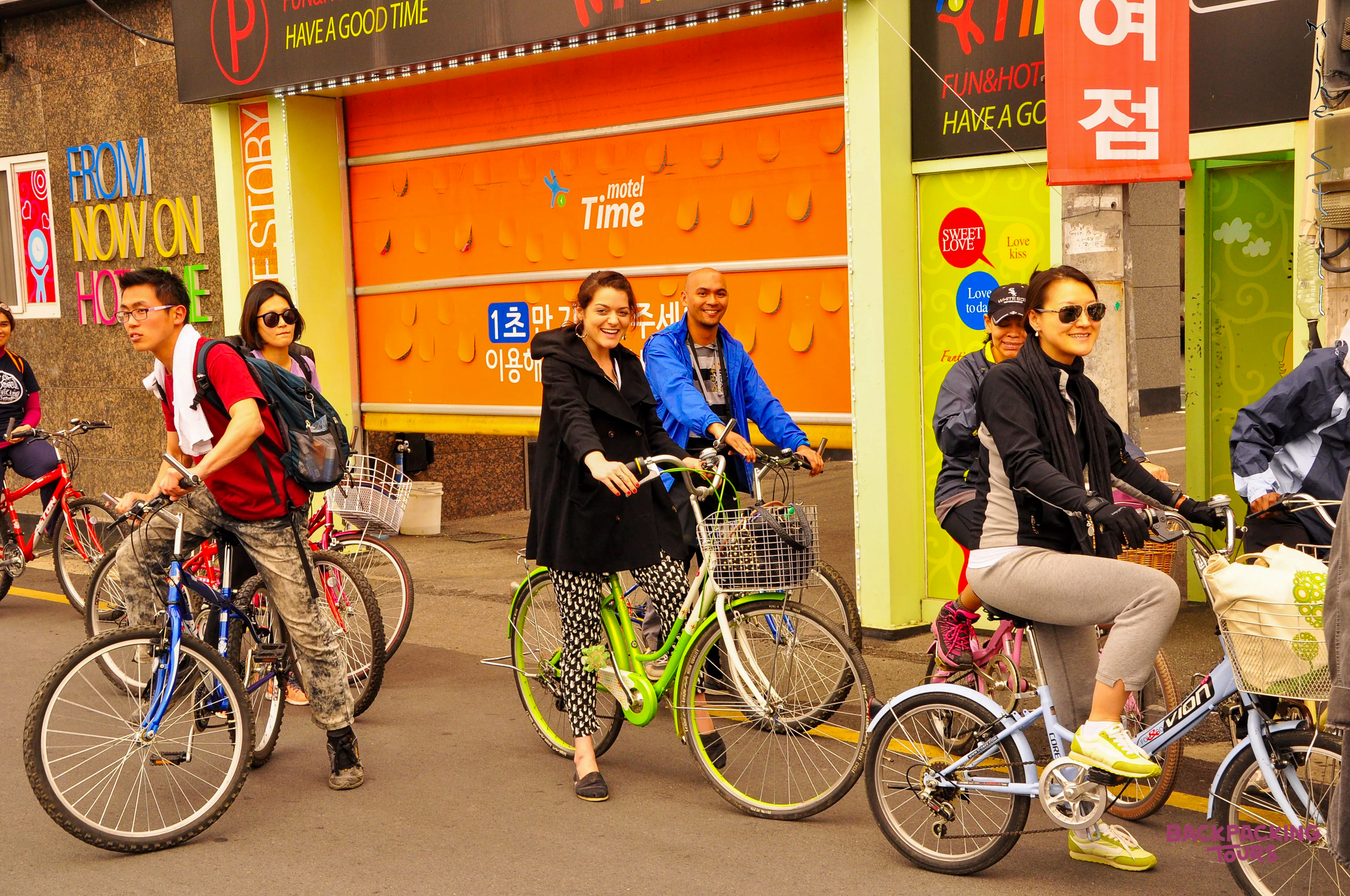 A group of happy backpackers enjoys a bike tour through the vibrant streets of Gyeongju, South Korea.