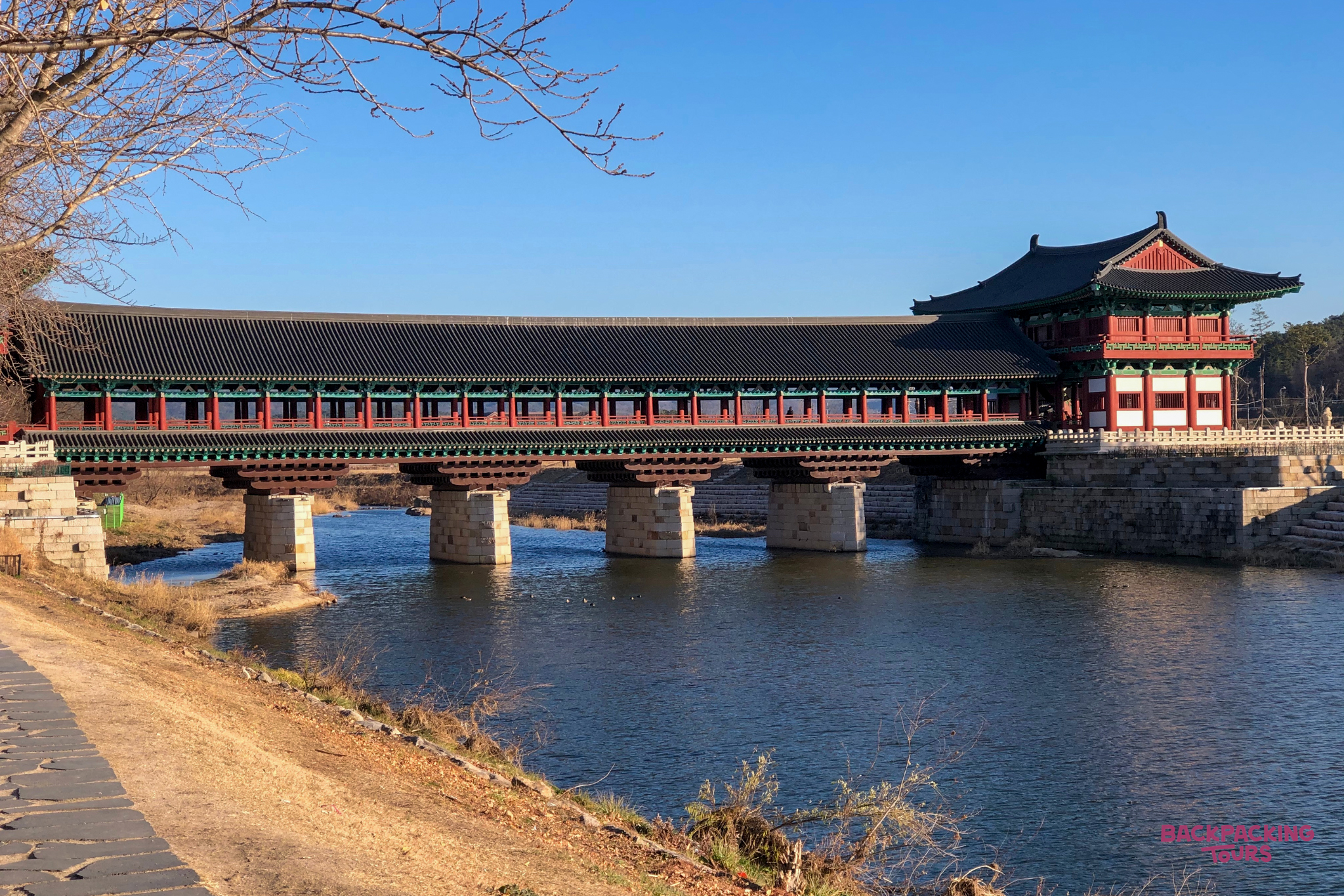 A beautiful traditional Korean covered bridge with a pavilion spans a calm river in Gyeongju.