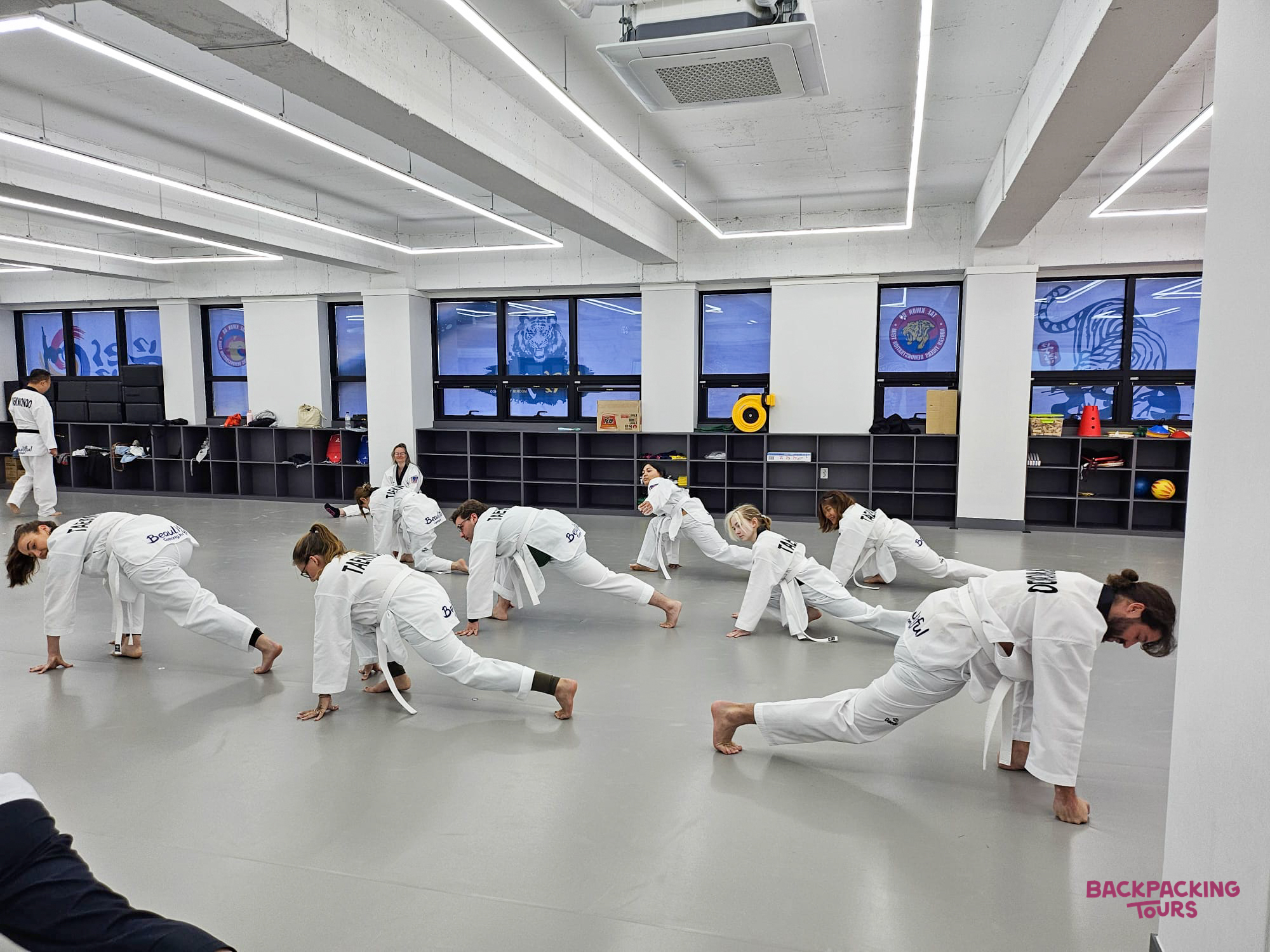 Travelers in white uniforms practice Taekwondo stretches during an engaging class in Gyeongju, South Korea.