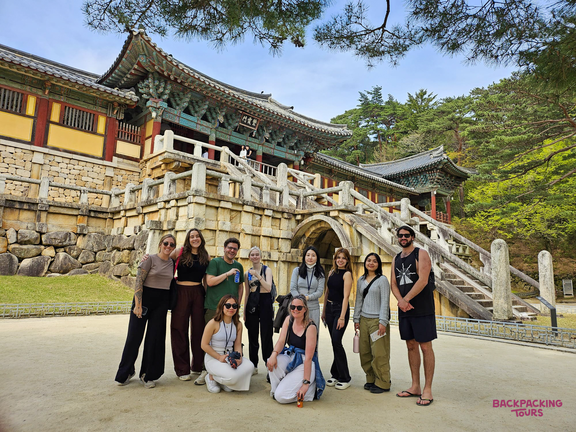 A happy group of travelers poses in front of the magnificent Bulguksa Temple in Gyeongju.