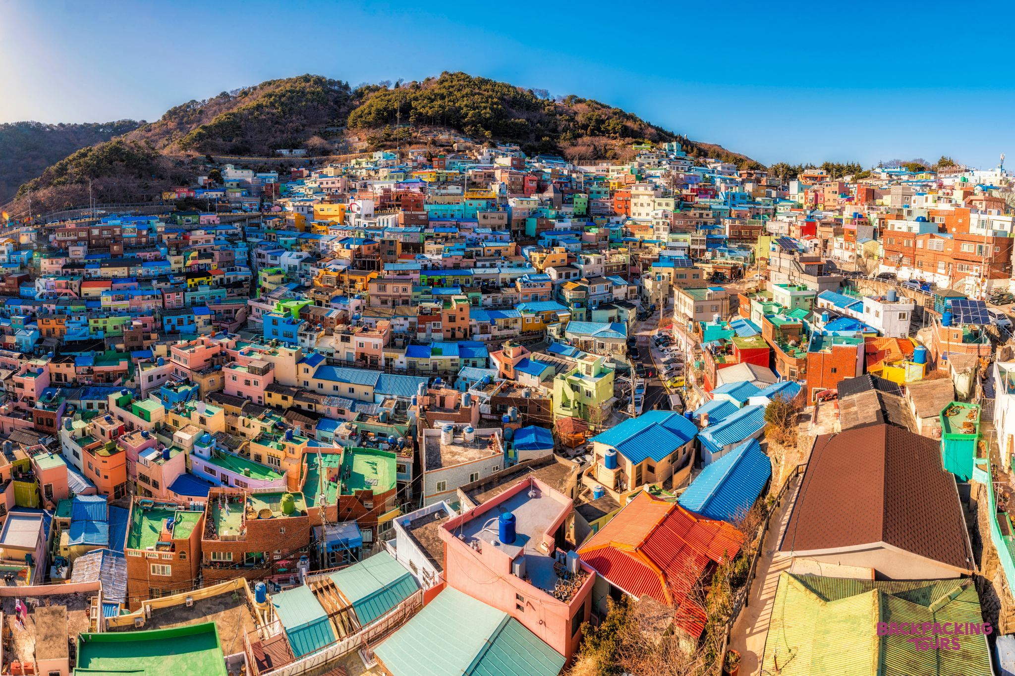 The vibrant, terraced houses of Gamcheon Cultural Village in Busan, South Korea, under a clear sky.