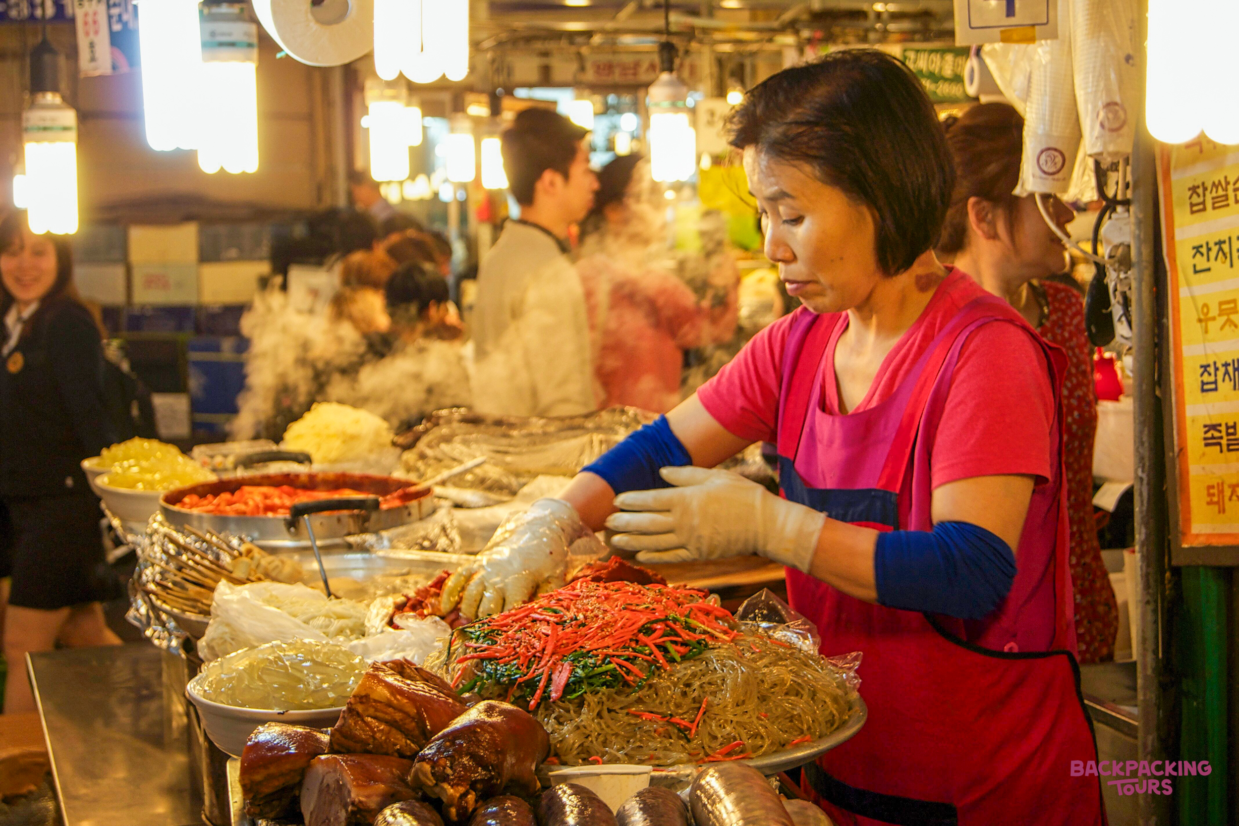 A woman prepares delicious traditional Korean food at a bustling market stall in Busan.