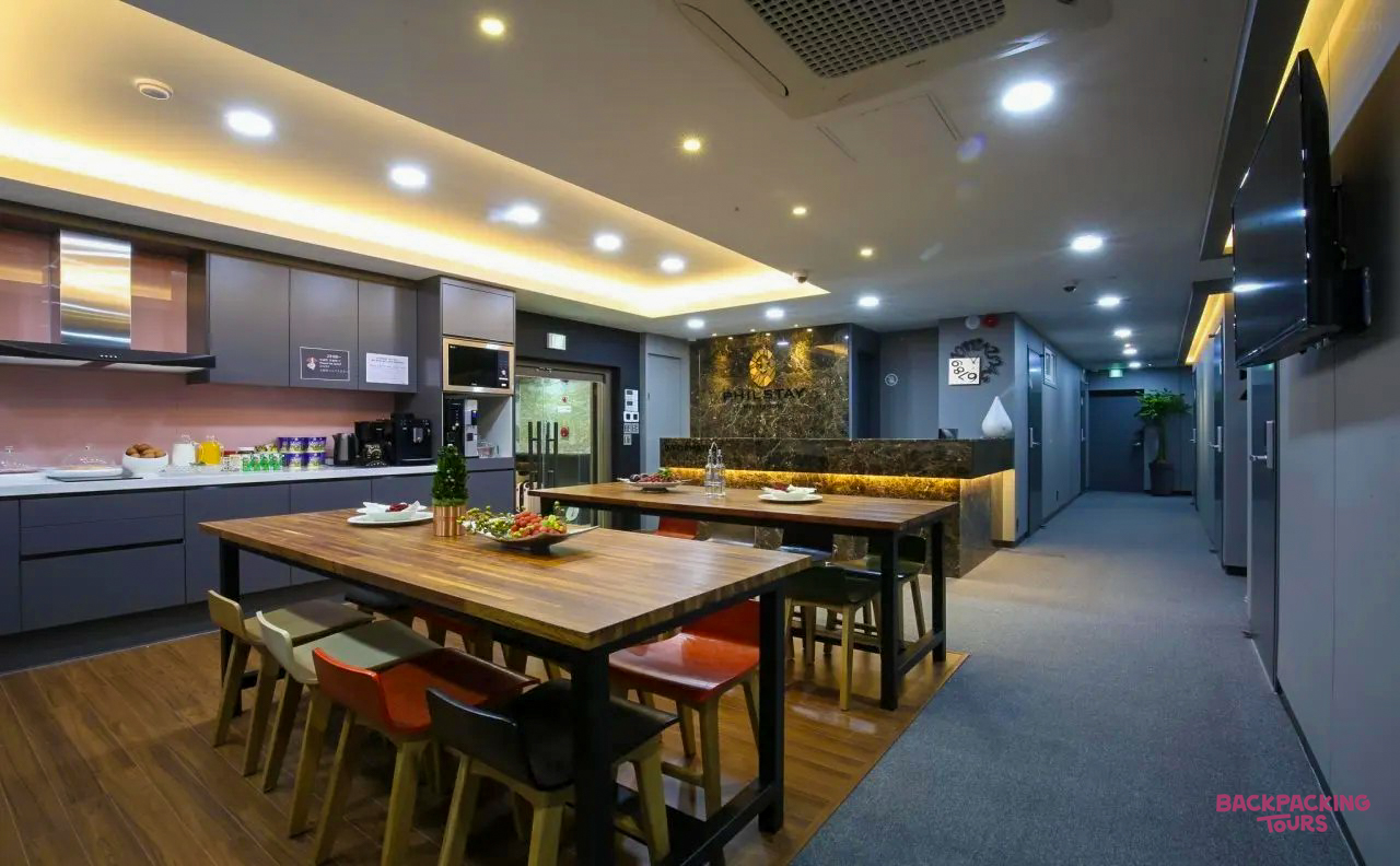 A modern and spacious hostel kitchen and dining area with wooden tables in Seoul.