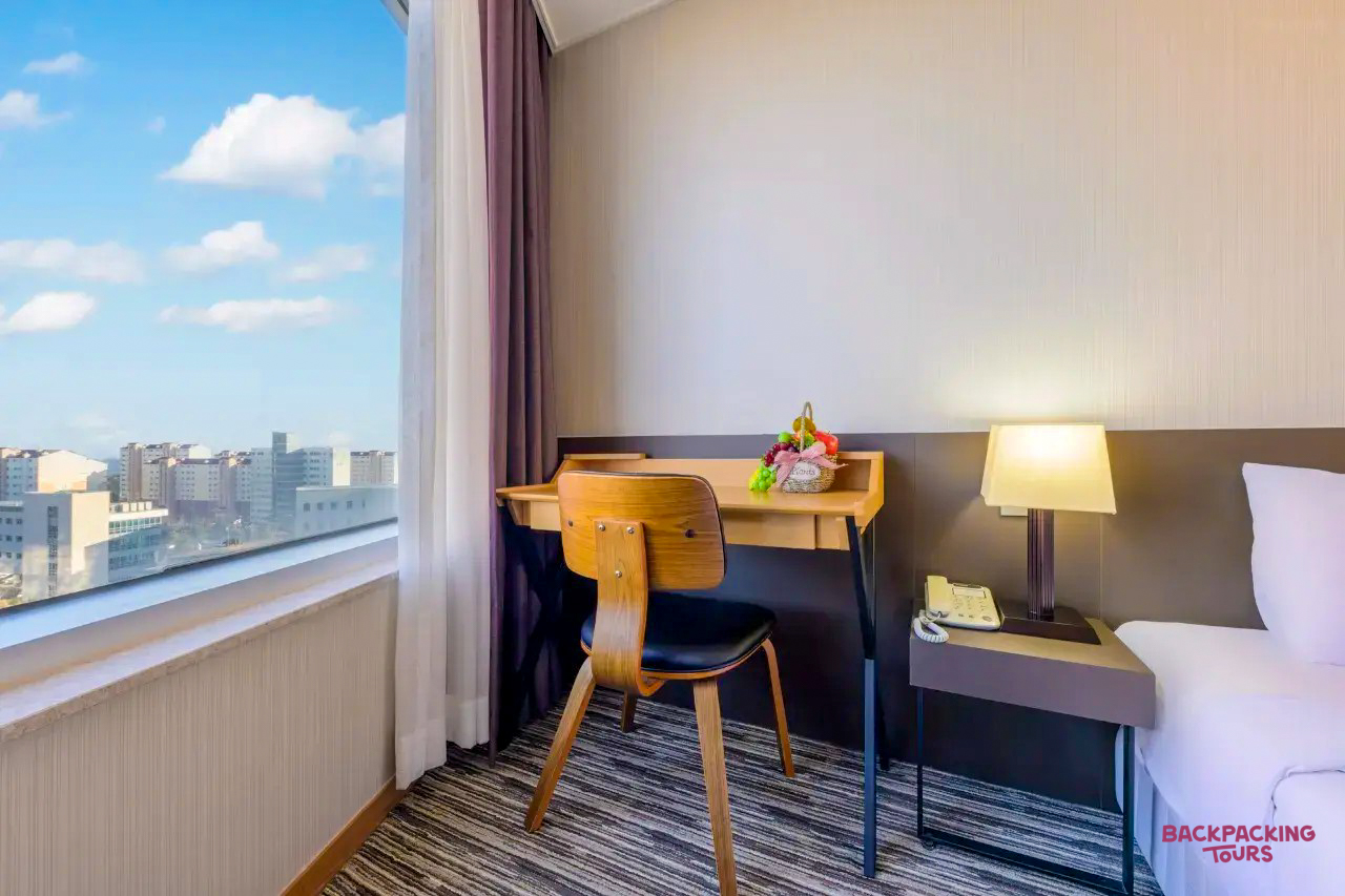 A bright, modern hotel room on Jeju Island, featuring a desk and a city view.