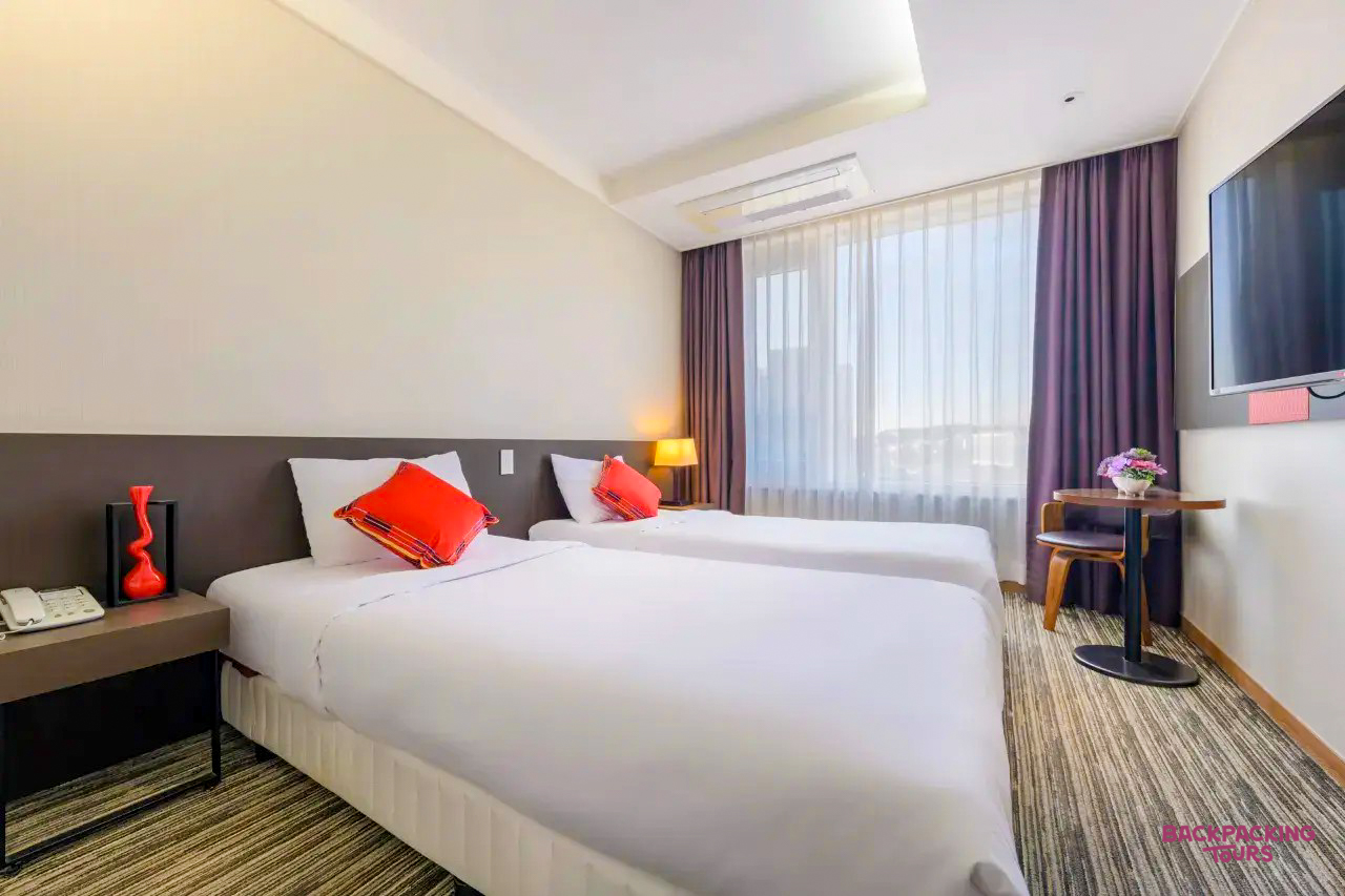 A modern hotel room on Jeju Island with two comfortable single beds and a bright window.