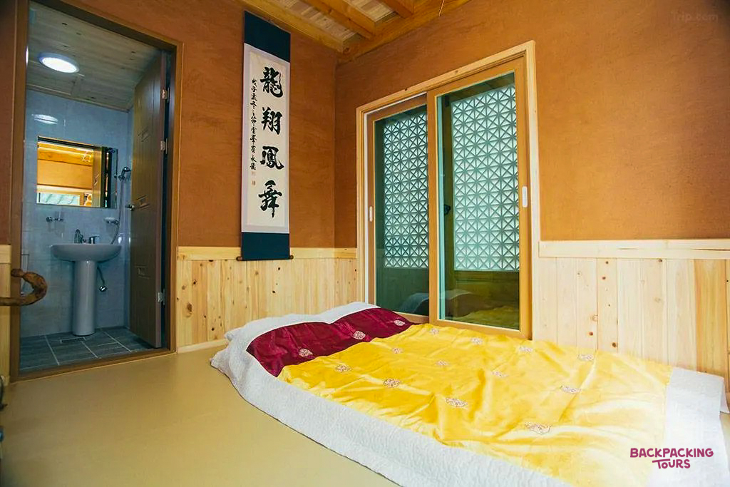 A traditional Korean hanok guesthouse room in Jeonju, featuring a comfortable futon bed and wooden details.