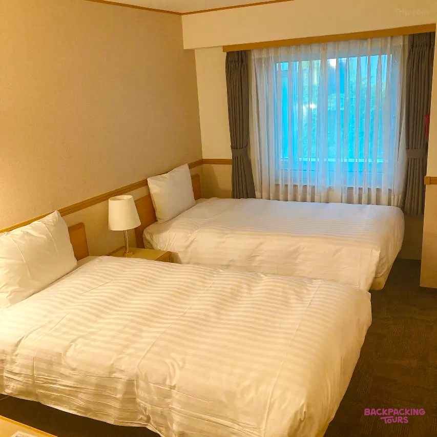 Two comfortable single beds in a tidy hotel room, offering a restful stay in Busan.
