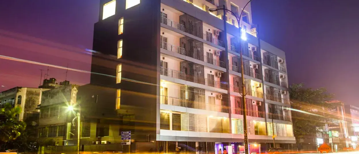 A modern building with illuminated windows and balconies on a busy Colombo street at night.