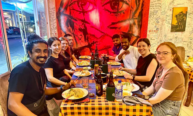 Eight happy backpackers enjoying a welcome dinner at a vibrant restaurant in Colombo.
