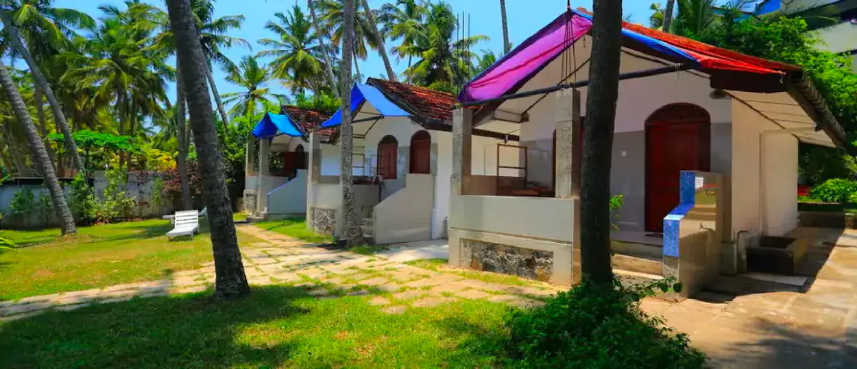 Tropical bungalows with vibrant roofs and palm trees on a sunny day in Weligama.