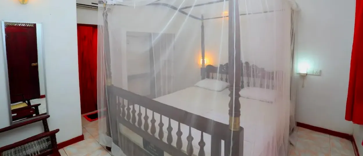 A comfortable hotel room in Unawatuna, Sri Lanka, with a four-poster bed and protective mosquito net.